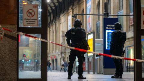 Zwei Polizisten stehen an einem gesperrten Ausgang des Wiesbadener Hauptbahnhofs. 