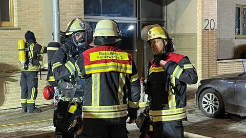 Feuerwehrleute stehen vor dem Haus und besprechen den Einsatz