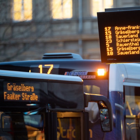 Busse stehen hinter einer elektronischen Fahrplan-Anzeige in Wiesbaden.