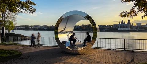 Die röhrenförmige Skulptur "Pixelröhre" am Rheinufer des Wiesbadener Stadtteils Kastel im Licht der herbstlichen Abendsonne.