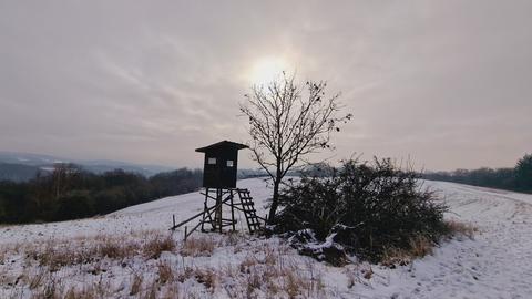 Ein Hochsitz und eine mit Schnee bedeckte Wiese.