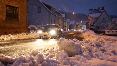 Auto fährt auf verschneiter Straße.