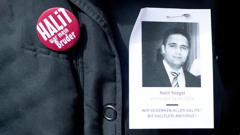 Button mit der Aufschrift "Halit war mein Bruder" steckt an einer Jacke, daneben ein Papier mit dem Portrait des Ermordeten.