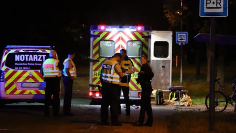 Sanitäter und eine Polizistin stehen vor ihren Einsatzwagen am Bahnhof