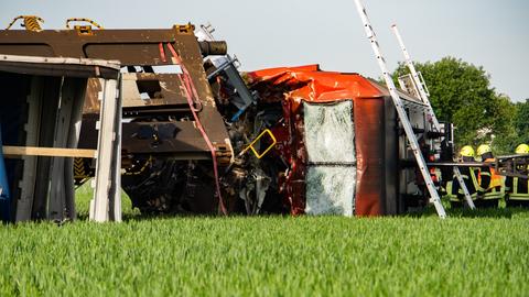 Eine Lok liegt neben den Gleisen auf einem Feld, Feuerwehr und Polizei stehen daneben.