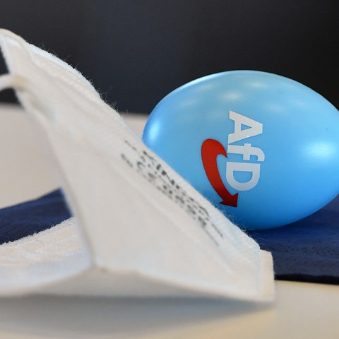 FFP2-Maske auf Tisch, daneben Ei mit AfD-Logo