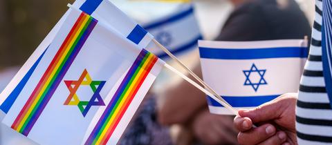 Die israelische Flagge mit Davidstern, eine israelische Flagge in Regenbogenfarben und eine ukrainische Flagge sind auf der Veranstaltung „Frankfurt vereint gegen Antisemitismus“ zu sehen.