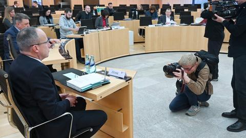 Fotografiert im Plenarsaal: Links im Bild von der Rückansicht Beuth und andere Personen. Rechts im Bild ein Kamerateam, das seine Kameras auf die Personen richtet.