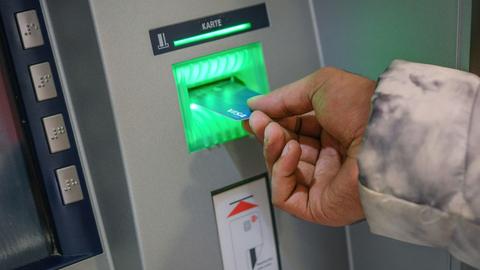 Jemand steckt eine Bezahlkarte in einen Geldautomaten