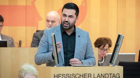 Taylan Burcu spricht stehend am Pult im Landtag.