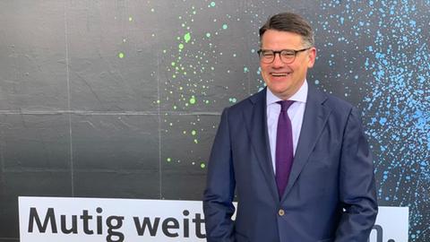 Boris Rhein lachend vor einer CDU-Plakatwand