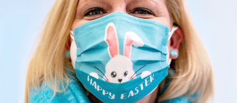 Eine Frau trägt einen Mund-Nasen-Schutz mit Ostermotiv.