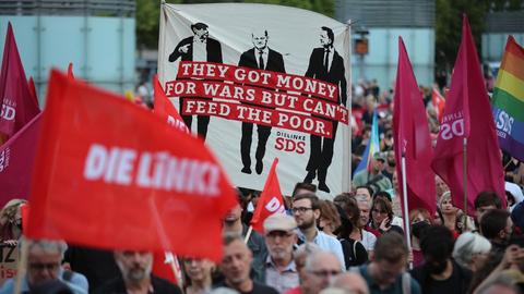 Protest gegen die Bundesregierung während einer Demo. Auf einem Banner steht z.B. "They got money for wars but can't feed the poor."