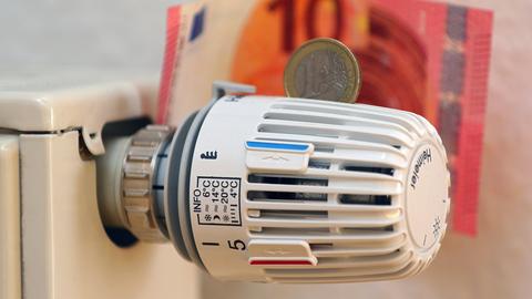 Das Thermostat eines Heizkörpers mit Geldscheinen und 1-Euro-Münze
