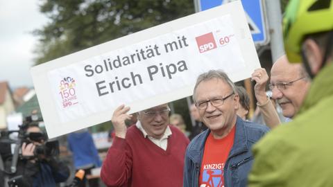 Erich Pipa steht vor einem Solidaritätsplakat