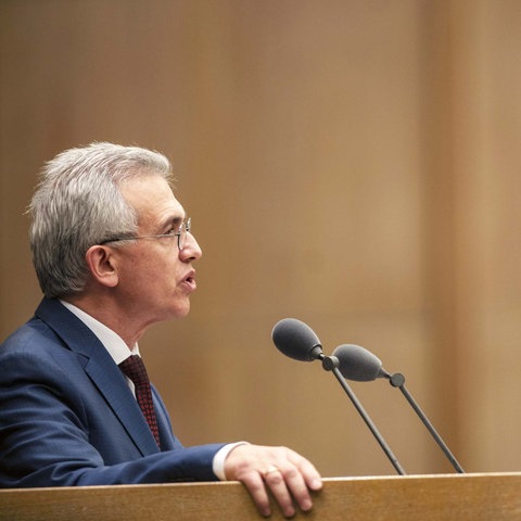 Peter Feldmann steht an einem Pult und spricht in Mikrofone. 