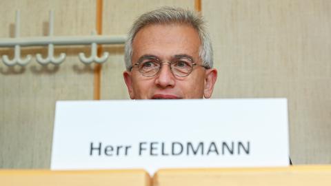 Peter Feldmann sitzt an einem Tisch - hinter einem Schild, auf dem "Peter Feldmann" steht. 