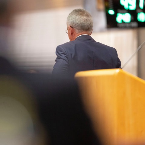 Feldmann dreht den Rücken zur Kamera und verlässt das Podium. 