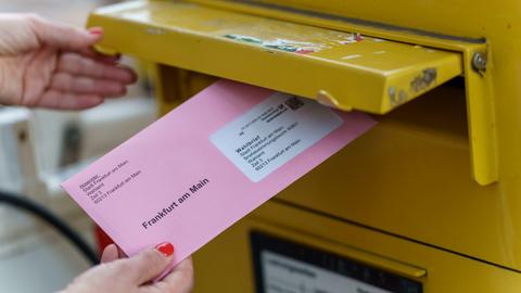 Eine Wählerin wirft ihren Briefwahl-Umschlag in einen Briefkasten. 