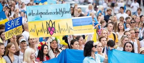 Demonstranten in den gelb-blauen Farben der Ukraine demonstrieren mit Fahnen und Schildern.
