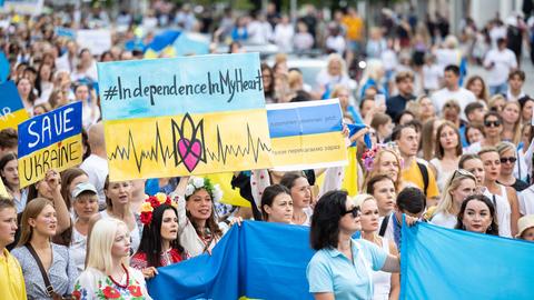 Demonstranten in den gelb-blauen Farben der Ukraine demonstrieren mit Fahnen und Schildern.