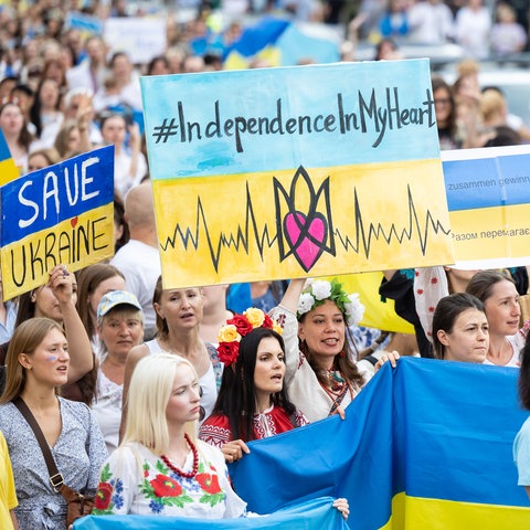 Demonstranten in den gelb-blauen Farben der Ukraine demonstrieren mit Fahnen und Schildern.