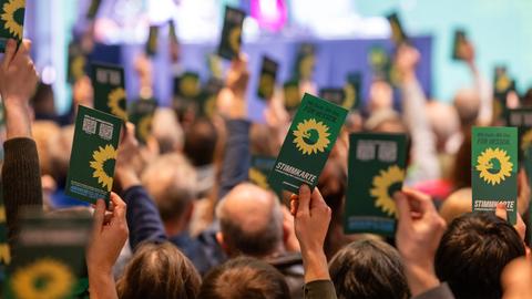 Parteimitglieder stimmen mit grünen Stimmkarten ab - einige halten die Karte hoch.