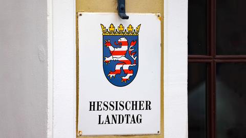 Rechteckiges Emailleschild an der Wand mit der Aufschrift "Hessischer Landtag" und darüber ein Wappen mit Löwe.