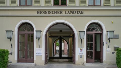 Drei Zugänge eines Gebäudes - mittig ein Rundtor, das zum Innenhof führt, rechts und links daneben Türen, die direkt in das Gebäude führen. Darüber steht "Hessischer Landtag" in großen Buchstaben.
