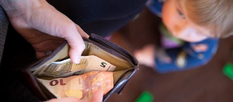 Ein Kind schaut auf einen Geldbeutel, in dem nur 15 Euro sind. 