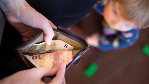 Ein Kind schaut auf einen Geldbeutel, in dem nur 15 Euro sind. 