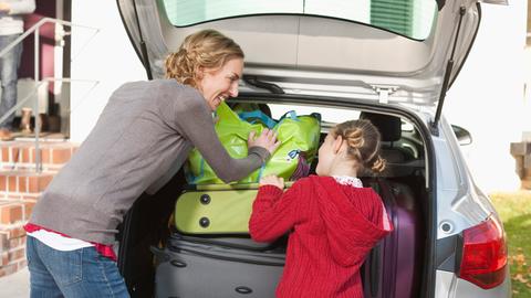Mutter und Kind packen Koffer in Auto