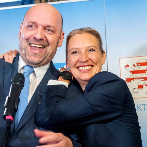 Links im Bild freuen sich Robert Lambrou und Alice Weidel von der AfD, rechts im Bild ein Stimmzettel mit einem Kreuz ber AfD