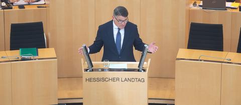 Ministerpräsident Boris Rhein steht im Landtag am Redepult und spricht.