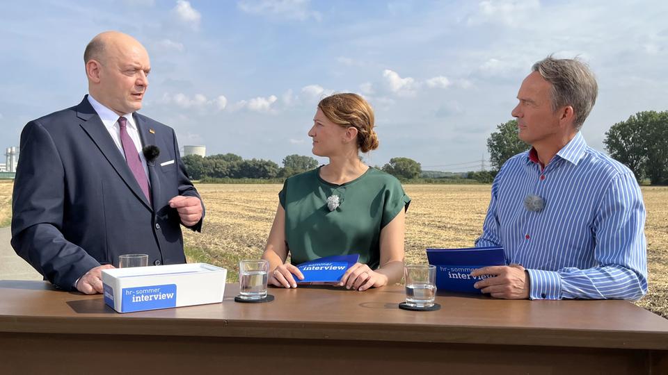 AfD-Landeschef Robert Lambrou (l.) mit den Moderatoren Sandra Müller und Tobias Häuser
