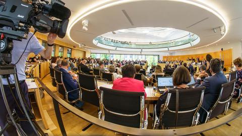 Fotot einer Plenarsitzung im hessischen Landtag. Im Vordergrund ein Kameramann an der Seite des Bildes.