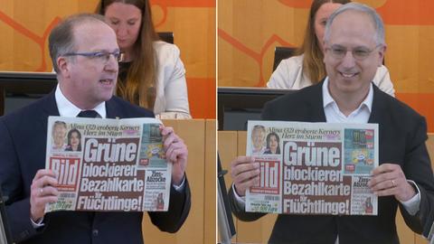 Die Landtagsabgeordneten Ingo Schon (CDU) und Yanki Pürsün (FDP) halten jeweils eine Bild-Zeitung hoch, auf der steht "Grüne blockieren Bezahlkarte für Flüchtlinge".