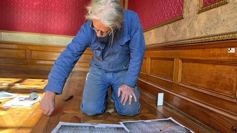 Holz- und Möbelrestaurator Michael Recker auf dem historischen Schmuckparkett des Landtags