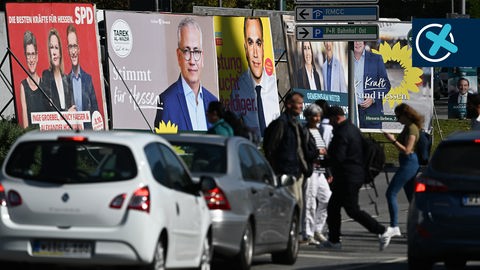 Plakate zur Landtagswahl in Hessen an einer Straße in Frankfurt, im Vordergrund Autos und Fußgänger