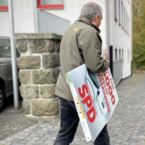 SPD-Chef Manfred Merz hängt die Wahlplakate der SPD ab.