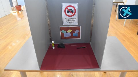 Ein Schild mit dem Schriftzug "Fotografieren und Filmen verboten!" hängt in einer Wahlkabine im.