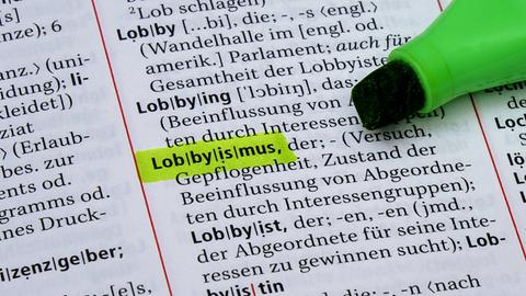 Foto von einer Seite eines Dudens, auf der das Wort "Lobbyismus" grün markiert ist. Daneben liegt ein grüner Textmarker. 