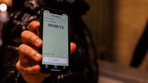Ein Besucher eines Clubs scannt mit der Luca-App auf seinem Smartphone einen QR-Code zum "Einchecken".