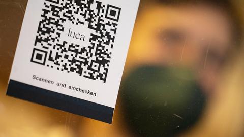 Ein Barcode, der mit der Luca-App zur Kontaktnachverfolgung gescannt werden kann, hängt in einem Einzelhandelsgeschäft an einer Schutzscheibe. 