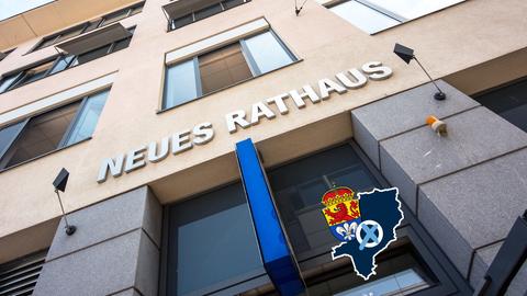 Foto von einem Gebäudeeingang, worüber "Neues Rathaus" steht - aus der Froschpersepektive fotografiert. Auf dem Bild eine kleine Grafik mit einer blau eingefärbten Fläche (Umriss der Stadt), dem Wappen der Stadt Darmstadt und einem Wahlkreuz.