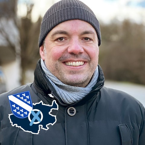 Christian Geselle Portrait. Auf dem Foto eine kleine Grafik mit einer blau eingefärbten Fläche (Umriss Stadt Kassel), dem Wappen der Stadt und einem Wahlkreuz.