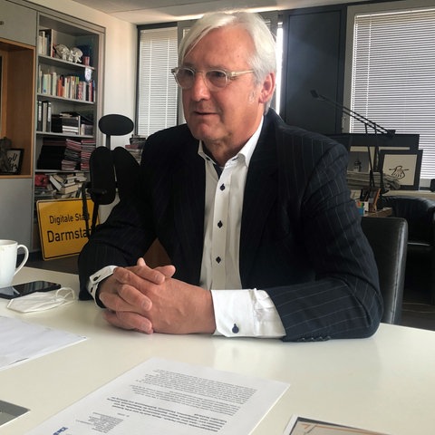 Der Grünen-Oberbürgermeister Jochen Partsch sitzt in seinem Büro an einem Tisch.