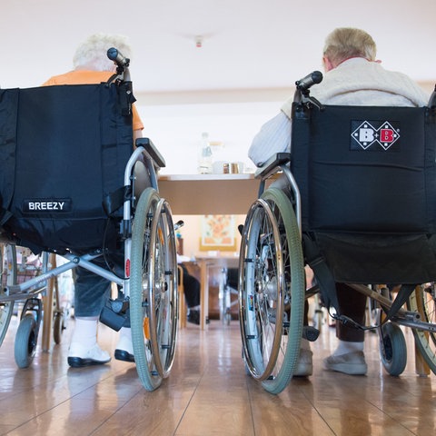 Zwei Bewohner eines Altenheims sitzen in Rollstühlen.