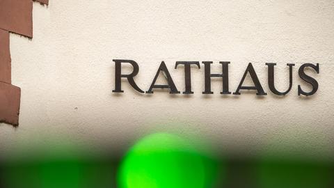 Foto: Das Wort "Rathaus" - einzelne Metallbuchstaben - an einer Hauswand. Am seitlichen Rand ist etwas Sandstein zu sehen. Am vorderen Rand ein grüner Lichtfleck, vermutlich von der Kamera.
