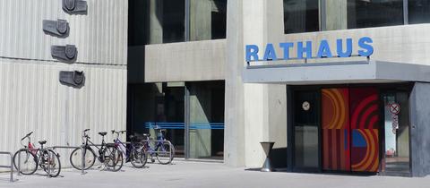 Zeitgenössisches Gebäude aus Beton mit farbigen Flächen. Über der Eingangstür steht groß "Rathaus". 